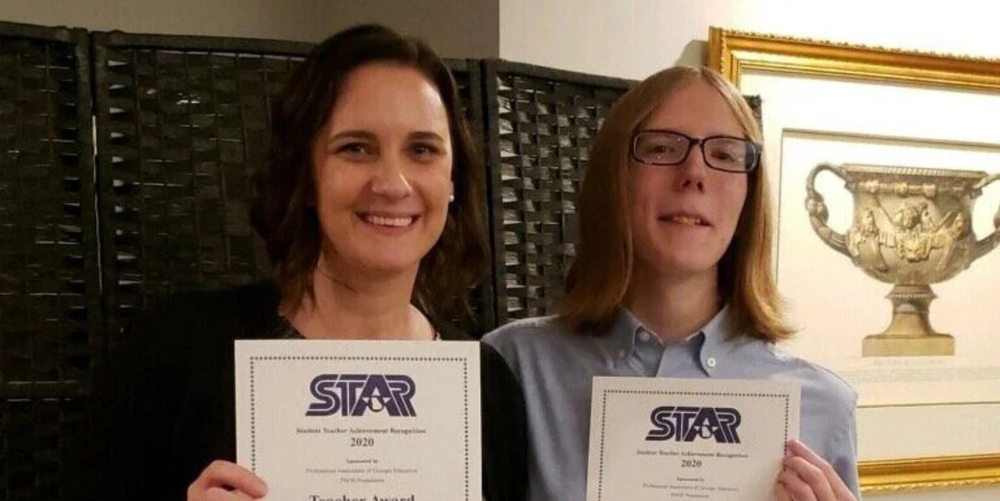 A teacher and student posed with certificates honoring them as STAR teacher and STAR student at a banquet.