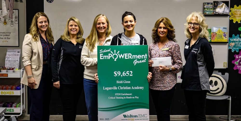 6 women smiling and holding a sign