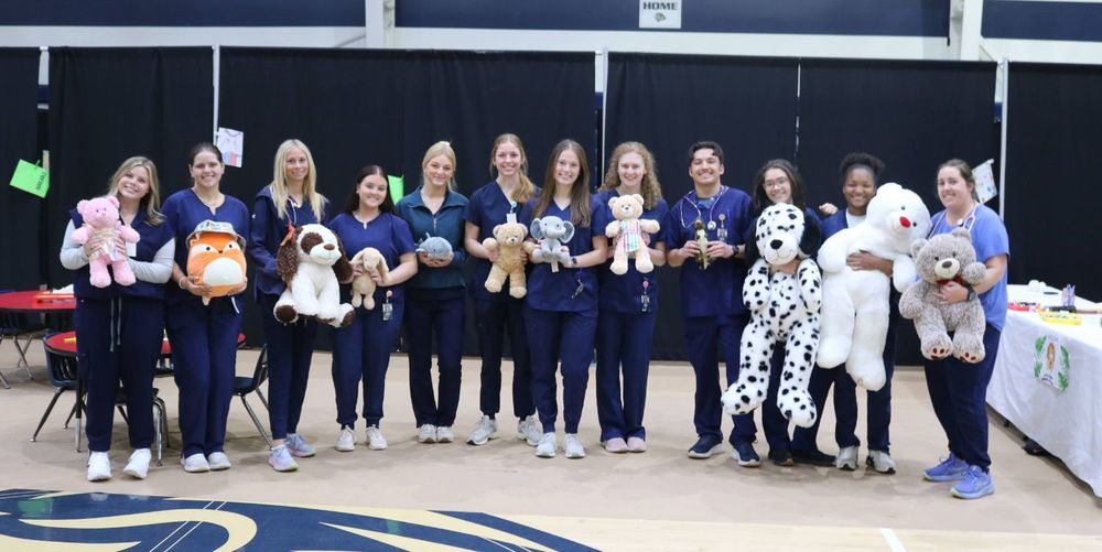 students smiling and holding stuffed animals