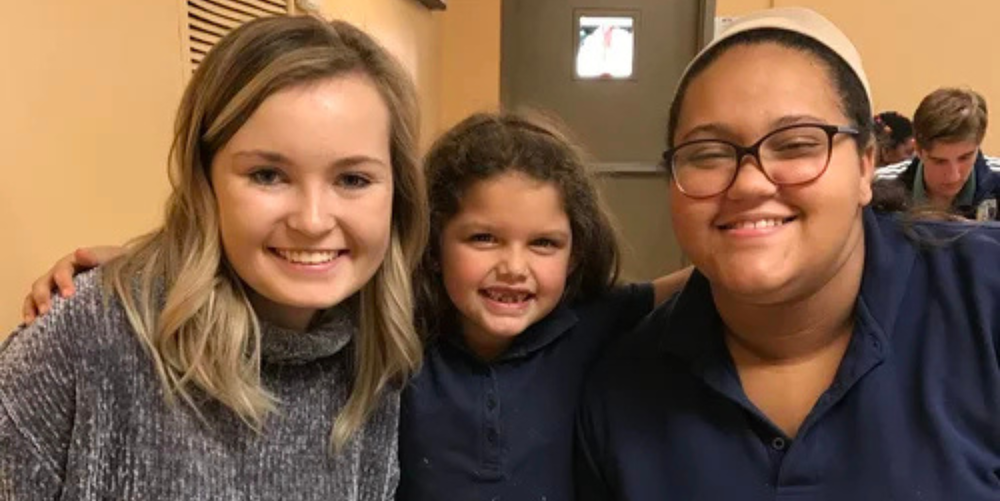 Three female students smile posing for a photo.