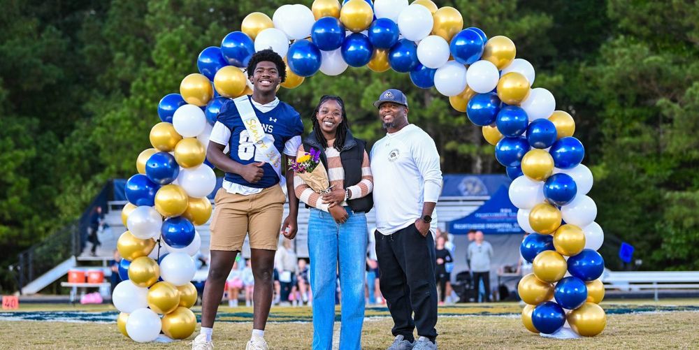 two men and a woman standing in front of a balloon arch