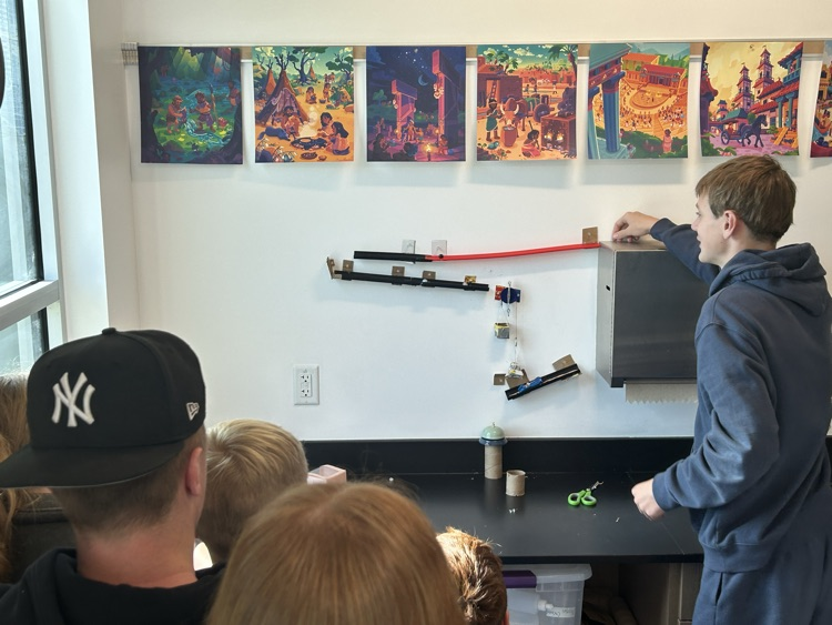 One student carefully starts his Rube Goldberg machine.