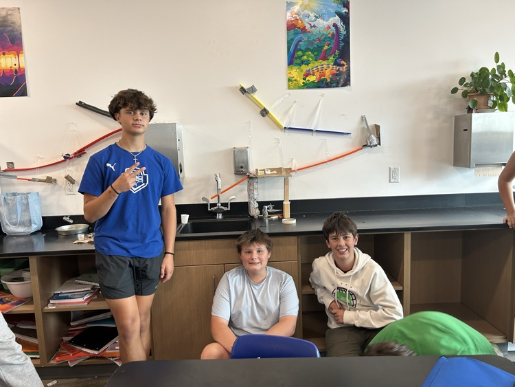 Three students pose with their Rube Goldberg machine.