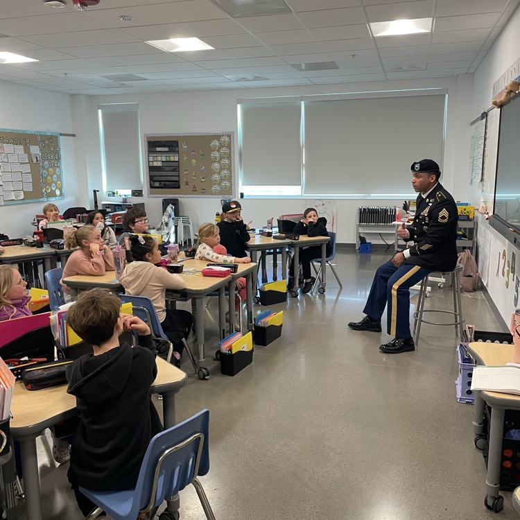 A man in uniform talks to a third grade class