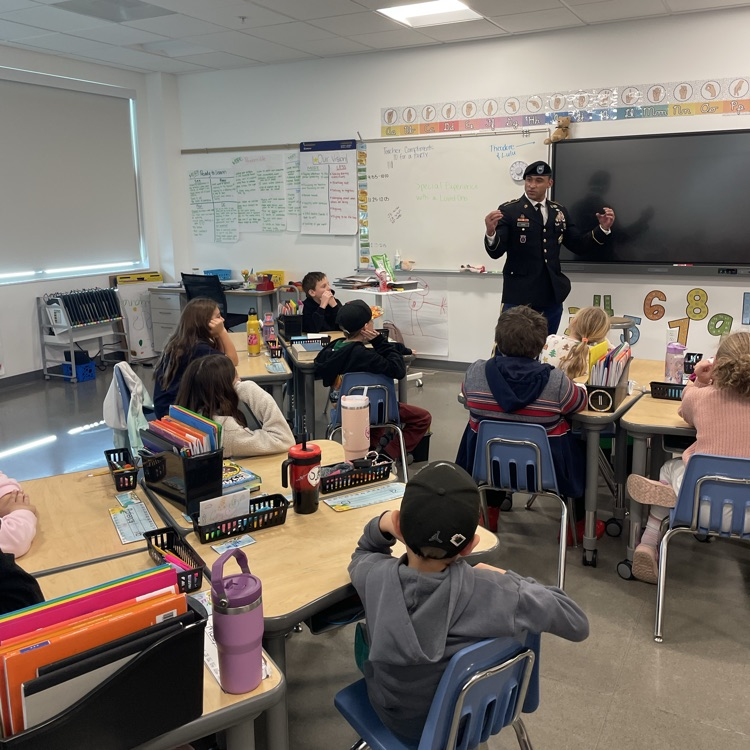 A man in uniform talks to a third grade class