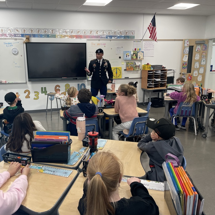 A man in uniform talks to a third grade class