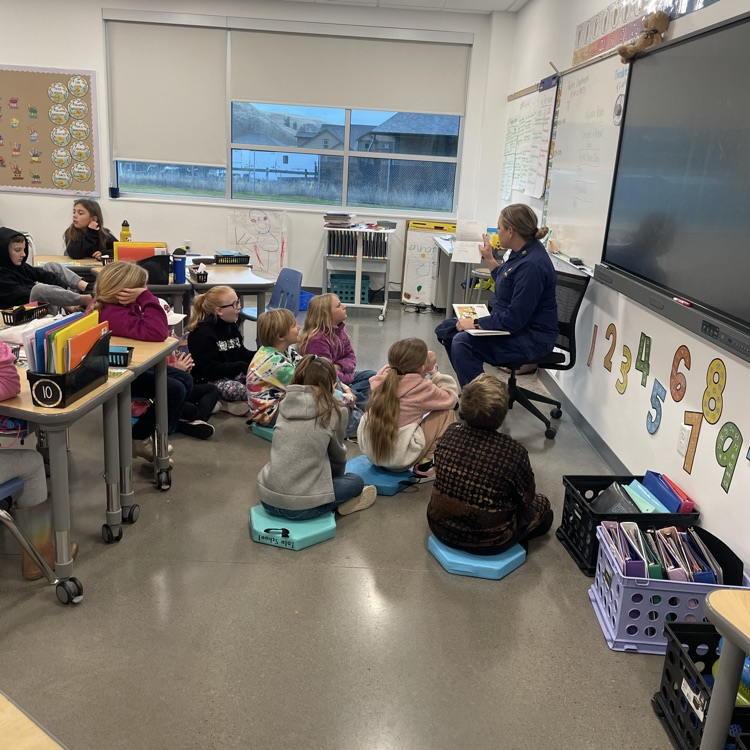 A woman reads to a third grade class