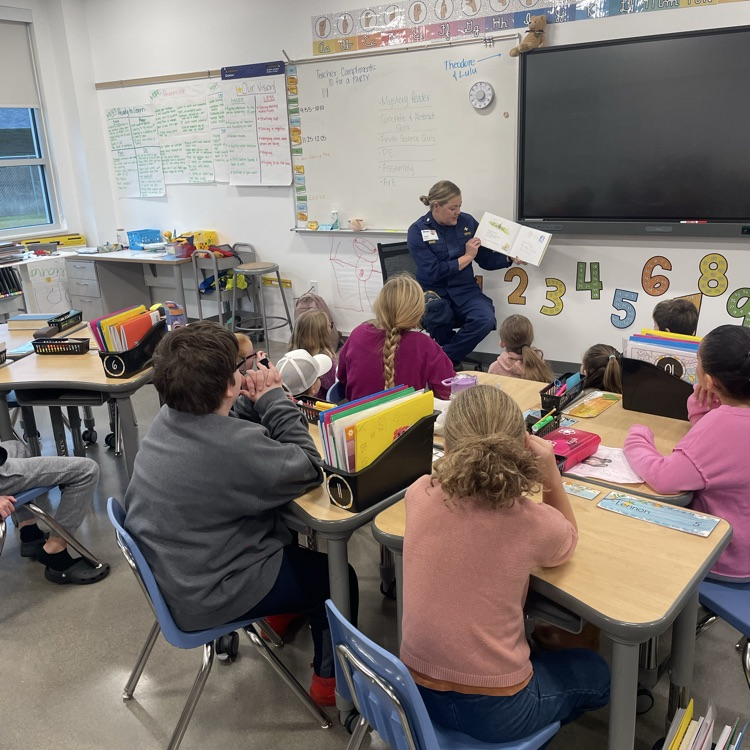 A woman reads to a third grade class