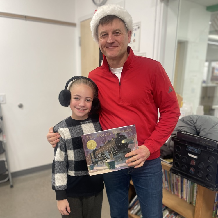 Two people stand smiling holding The Polar Express