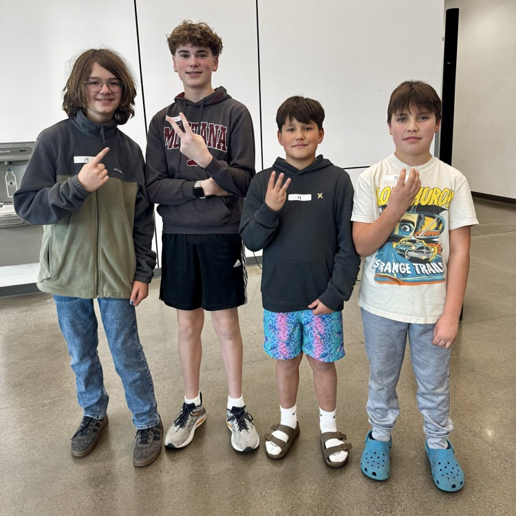 four students from the school spelling bee, pictured holding their place with their hands