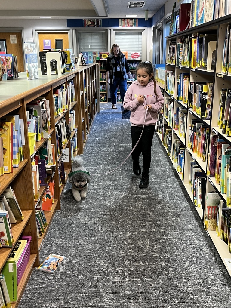 girl walking dog through library