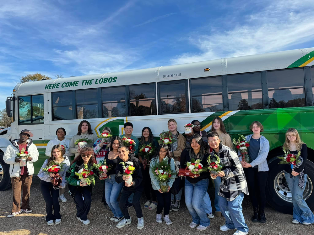 Longview ISD FFA students stand in front of a district branded school bus