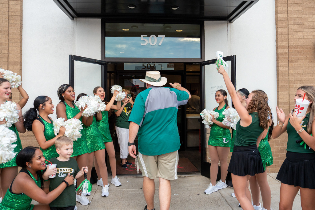 Coach King walking through the rally line of Viewettes and cheerleaders to Chick-fil-A.