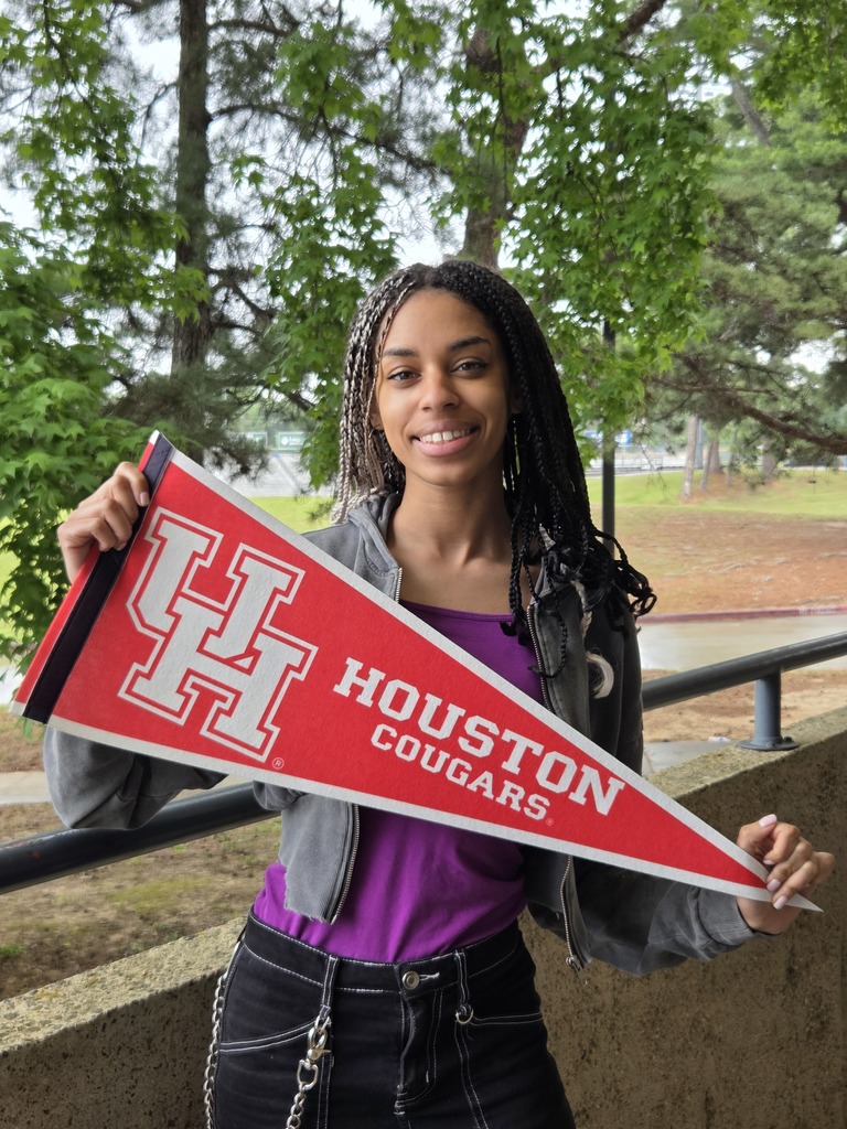 Ellani is holding a large University of Houston pennant with trees in the backdrop.