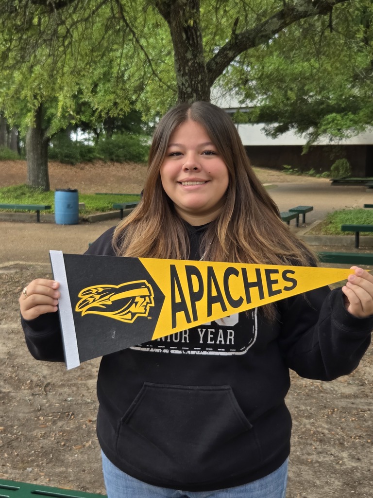 Brianna is holding  a yellow and black Tyler Junior College pennant that says Apaches