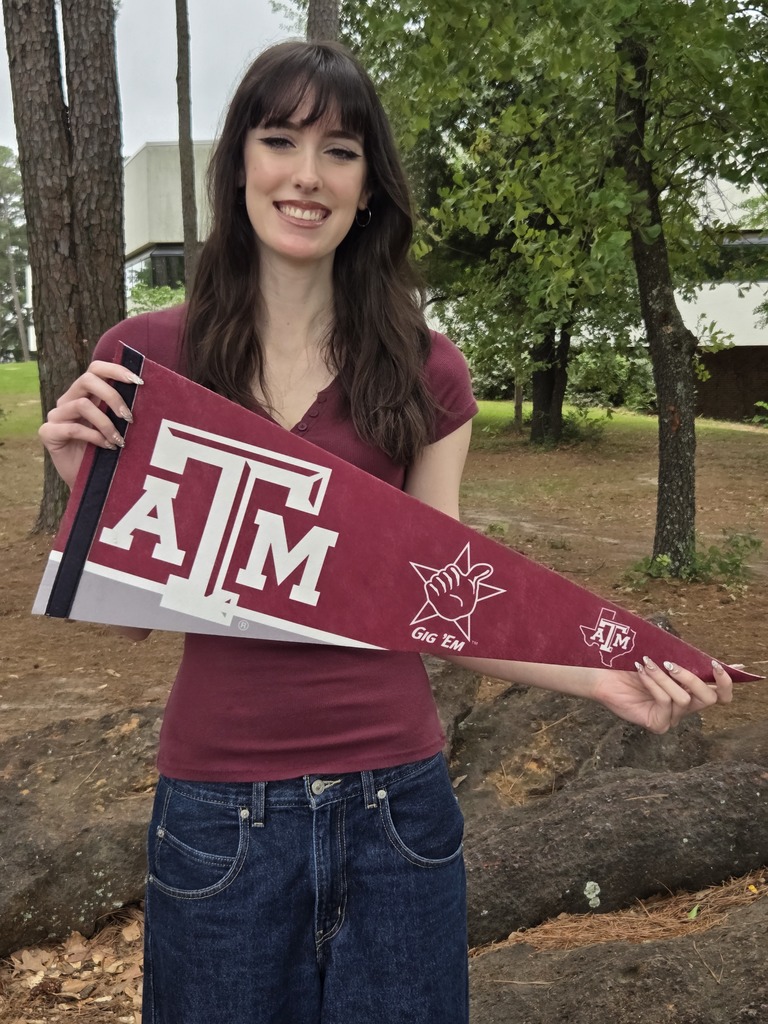 Gia is wearing a maroon shirt and holding a Texas A&M pennant.