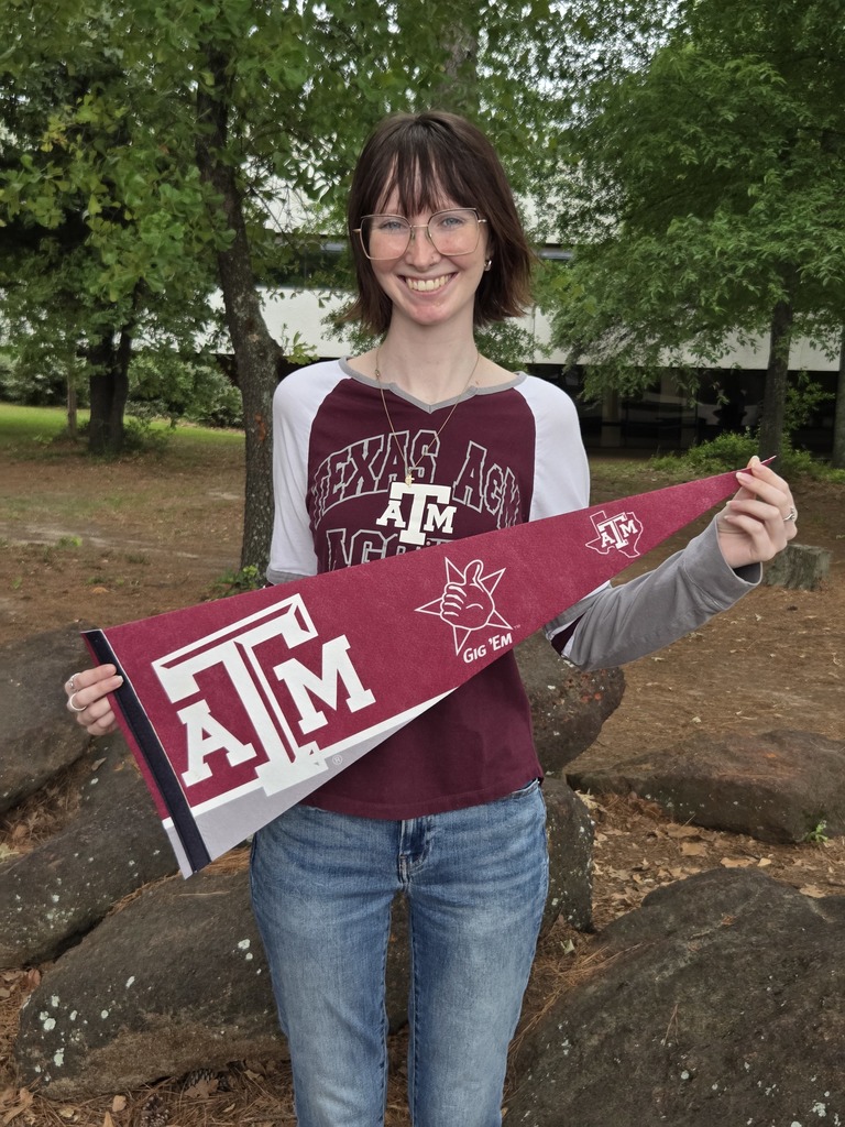 Savannah is wearing a Texas A&M shirt and holding a Texas A&M pennant