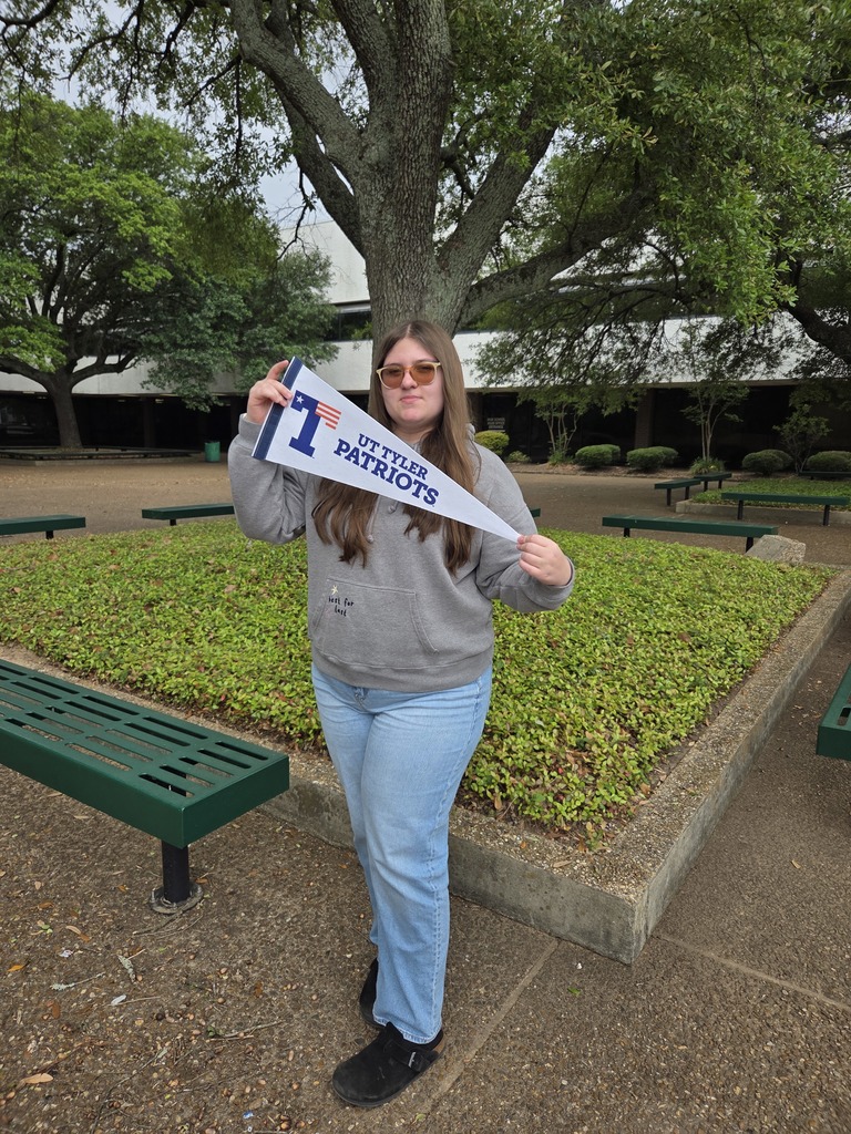 Hailie is holding a UT Tyler Pennant that is white with blue letteers.