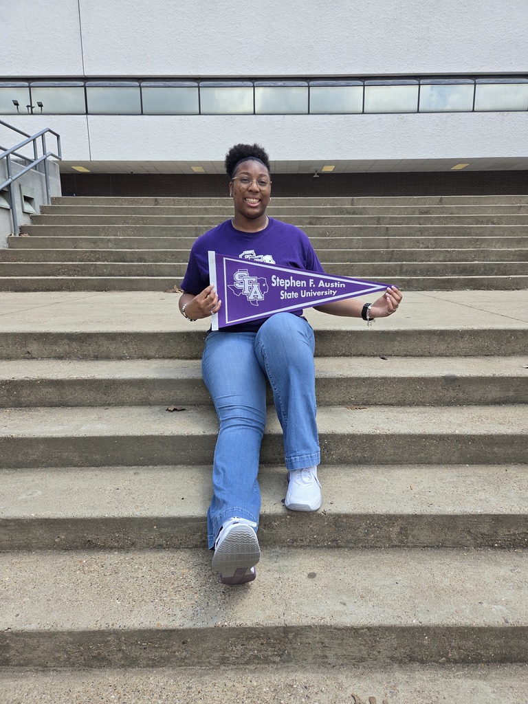 Savannah sitting on a large staircase outside wearing her purple SFA shirt and holding a SFA pennant.