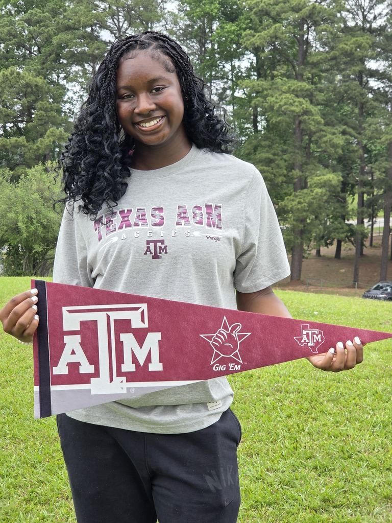 Kennedi is wearing a grey Texas A&M shirt and holding a maroon Texas A&M pennant