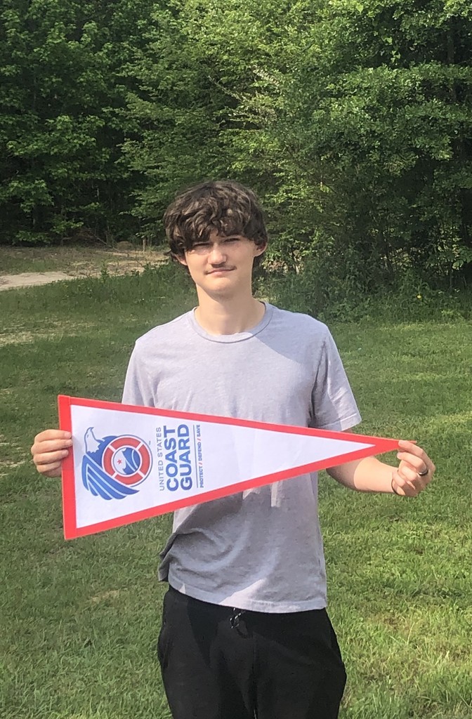 Noah Bradley standing outside holding a coast guard pennant