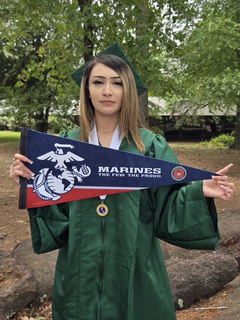Kayla is holding a marines pennant and wearing her cap and gown