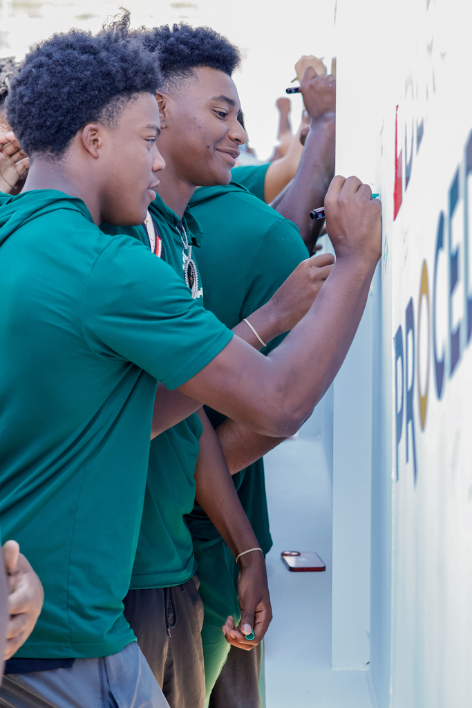 Senior football players signing the Trent Williams Multipurpose Indoor Facillity.