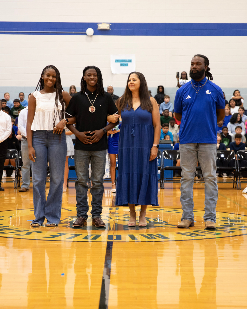 Four educators standing together and smiling on a gymnasium basketball court during a school event.