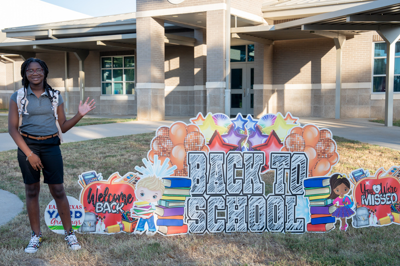 student by back to school sign