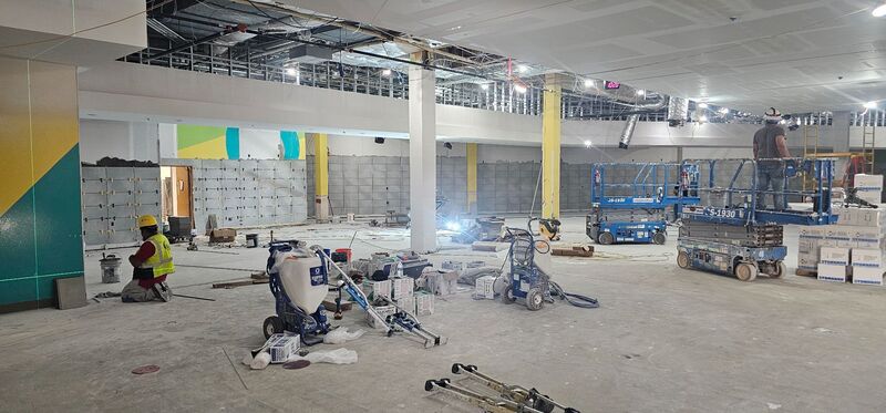 Crews work on wall and ceiling finishes inside Longview High School's cafeteria during summer construction.