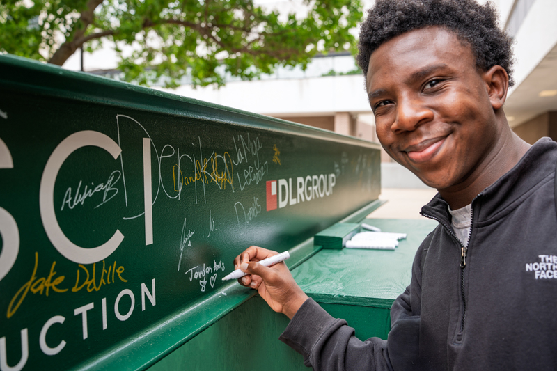 student signing construction beam