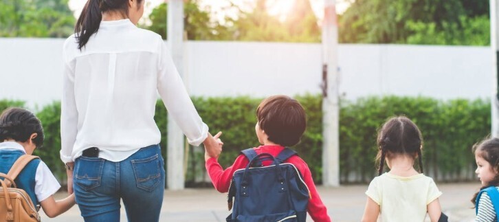 a woman walking with student children