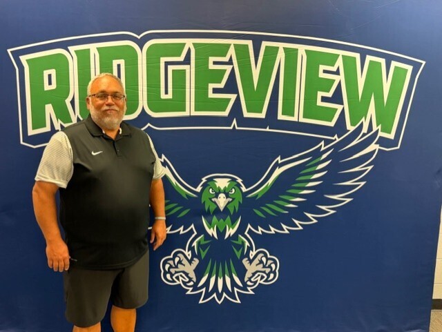 Man standing next to a blue backdrop with the word "Ridgeview" and a graphic of an eagle.