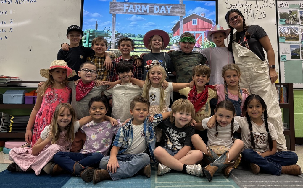 A classroom with a "FARM DAY" sign. Children in costumes sit and stand with an adult.