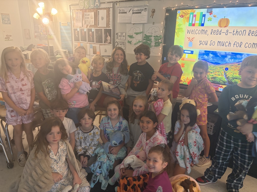 A classroom with children in pajamas posing for a group photo in front of a screen.