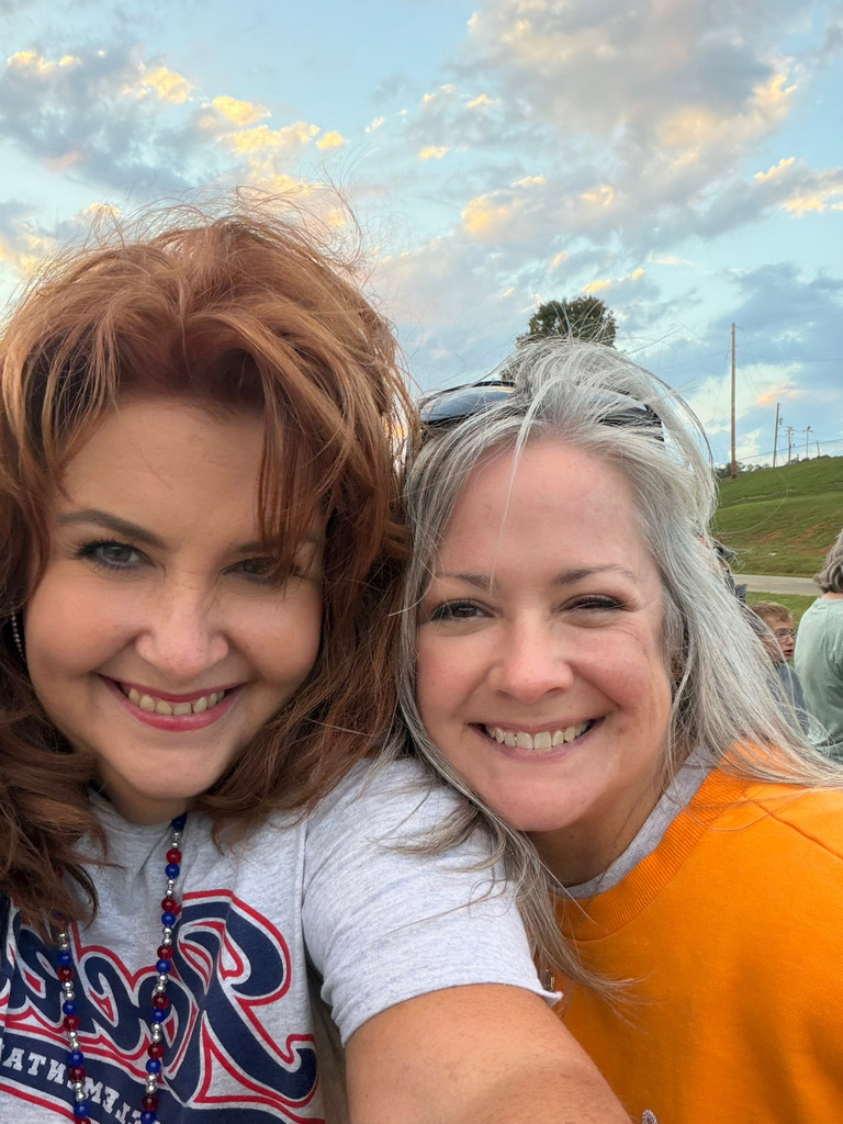 Two women smiling and posing for a photo with a sunset in the background.