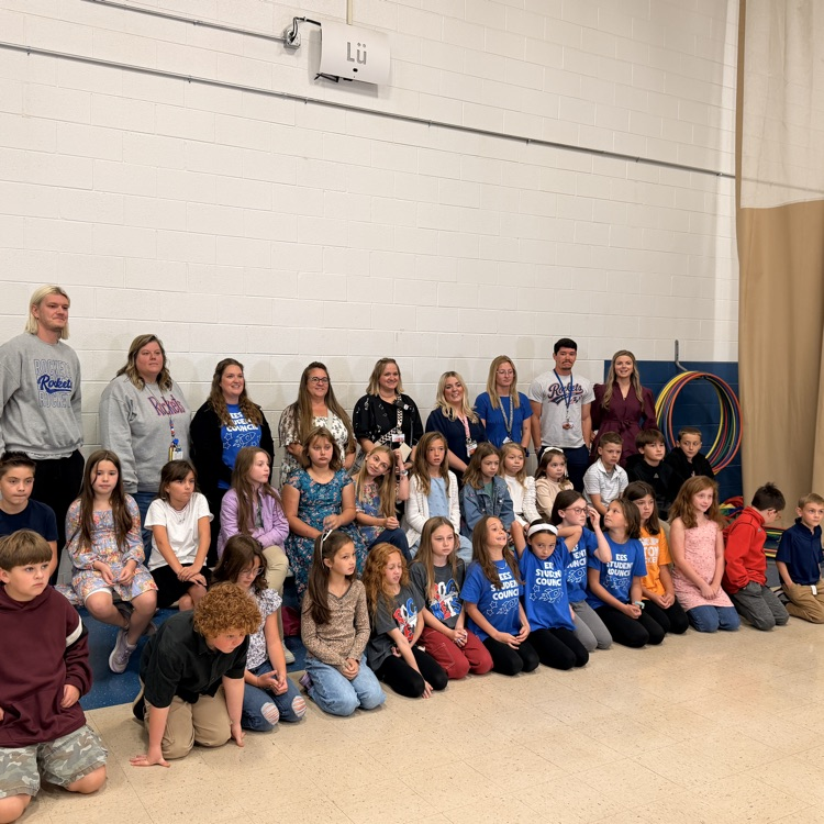 Group of students, teachers, and a principal posing for a photo in a gymnasium.