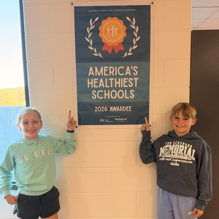 Two children standing by a banner saying "America's Healthiest Schools 2026 Awardee."