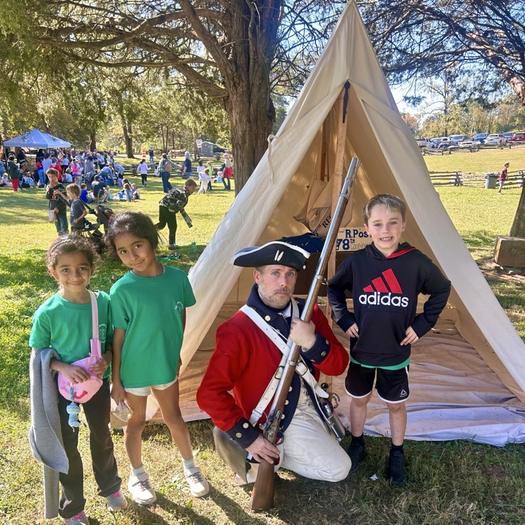 Four children and a man in a colonial costume pose in front of a teepee.