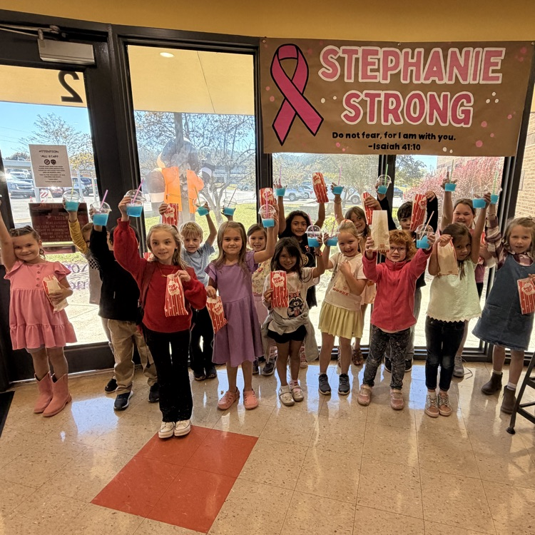 Children in school uniforms stand in a hallway, holding bags. A pink ribbon banner reading Stephanie Strong is above them.