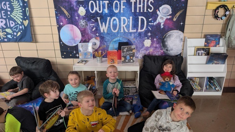 Students reading in front of poster that says "Out of this World"