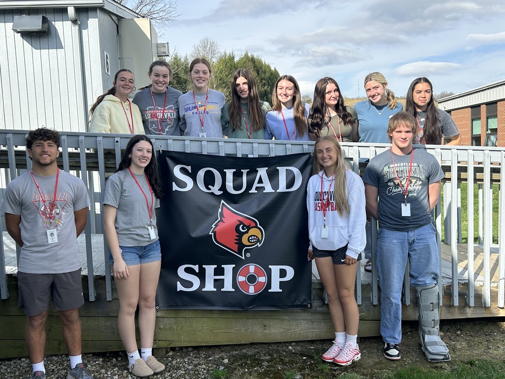 Students standing outside the Squad Shop posed with the sign.