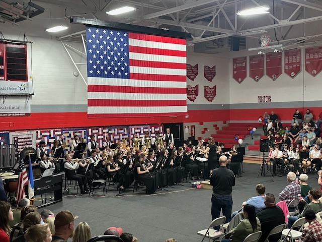 Photo of a band performance with large American flag overhead.