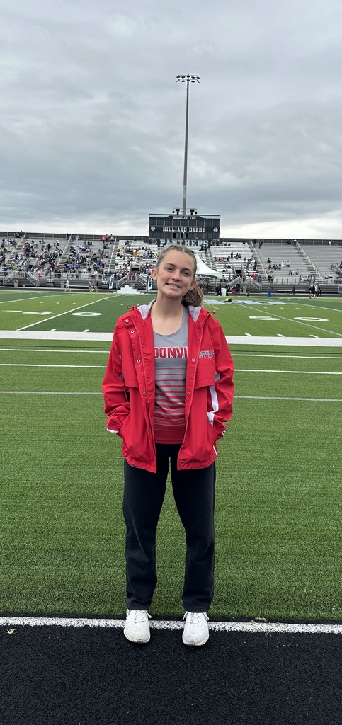Aria standing in front of the football field bleachers on track after a race. 