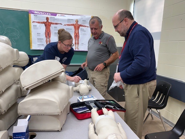 Staff members practicing CPR on baby dummy. 