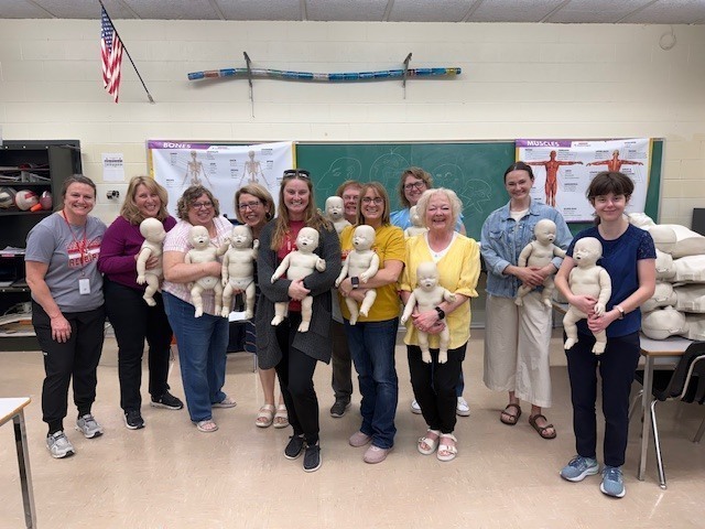 Group of staff members holding baby dummies. 