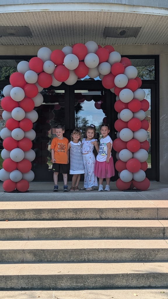 Students under a balloon arch outside of the school.