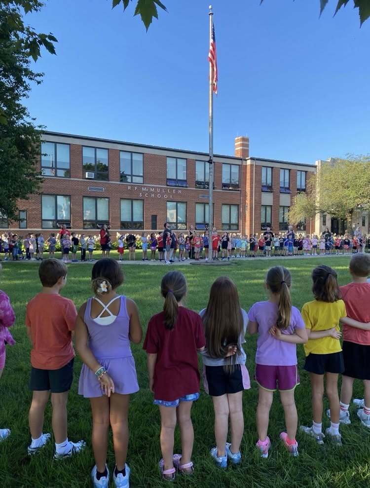 Students gathered around the flag pole outside of school.