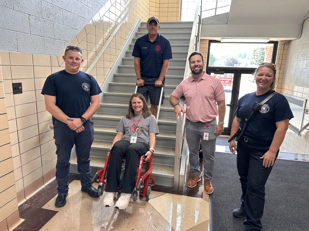 McMullen staff and LFD fire fighters infront of stairs with stair climber. 