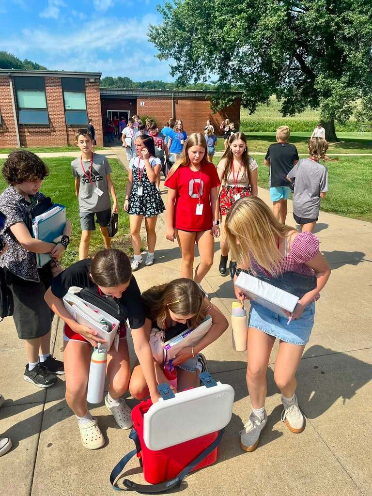 Students outside of the high school grabbing popsicles from a cooler. 